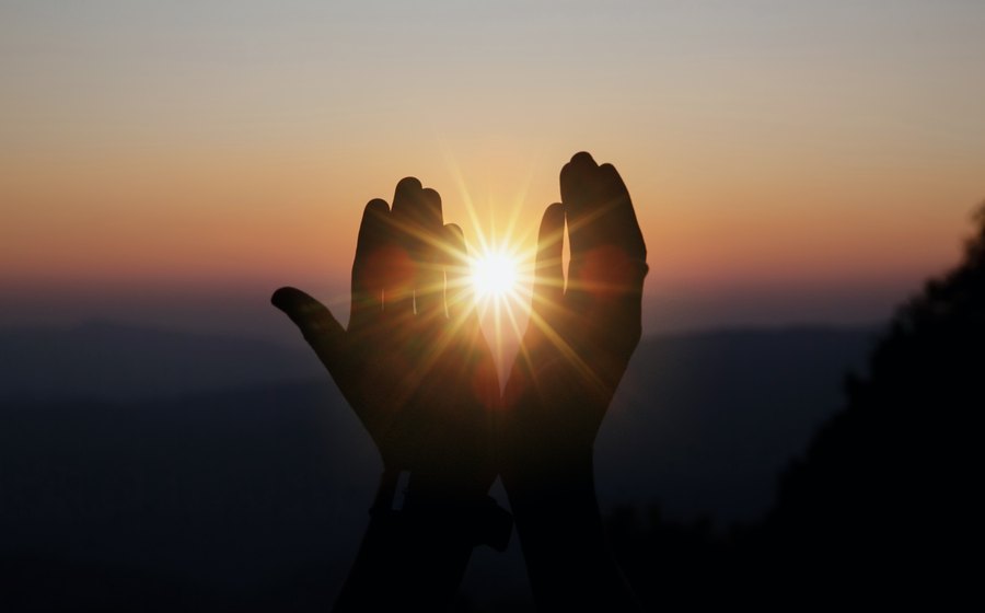 Manos abiertas al atardecer como signo de transformación